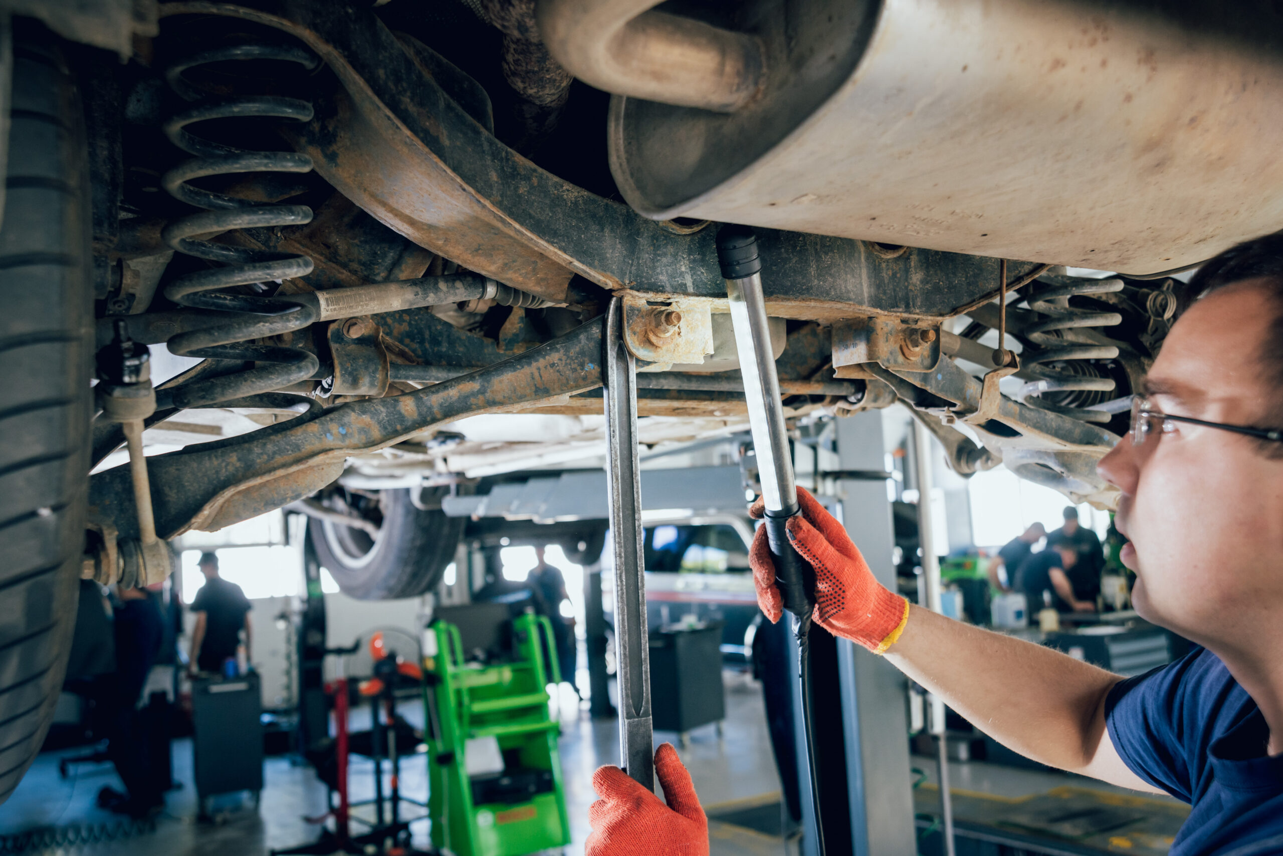 Mechanic inspecting vehicle suspension components underneath